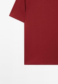 Bordeaux bomulds t-shirt med korte ærmer, der har en glat tekstur og en ren, rund udskæring. Enkel og ensfarvet design.