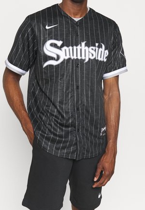 Mann trägt schwarzes, nadelgestreiftes Baseball-T-Shirt mit Text "Southside" und schwarze Shorts mit weißem Nike-Logo.