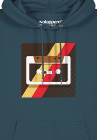 Türkise Kapuzenjacke mit einem Grafikdesign eines Kassettentapes in Weiß, Braun, Gelb und Rot auf einem geometrischen Hintergrund mit diagonalen Streifen.