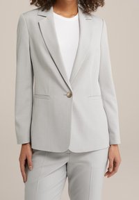 Ljusgrå blazer med slagna revers, en knappstängning och två framsidor fickor. Slät tyg med en skräddarsydd passform.