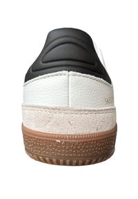 Fehér és fekete sneaker, bőr- és velúr textúrával, gumitalppal, amelyen mintás tapadás és texturált sarokkiemelés található.
