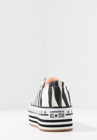 Baskets en toile à rayures noires et blanches avec une semelle épaisse, arborant le logo Converse All Star et une texture lisse.