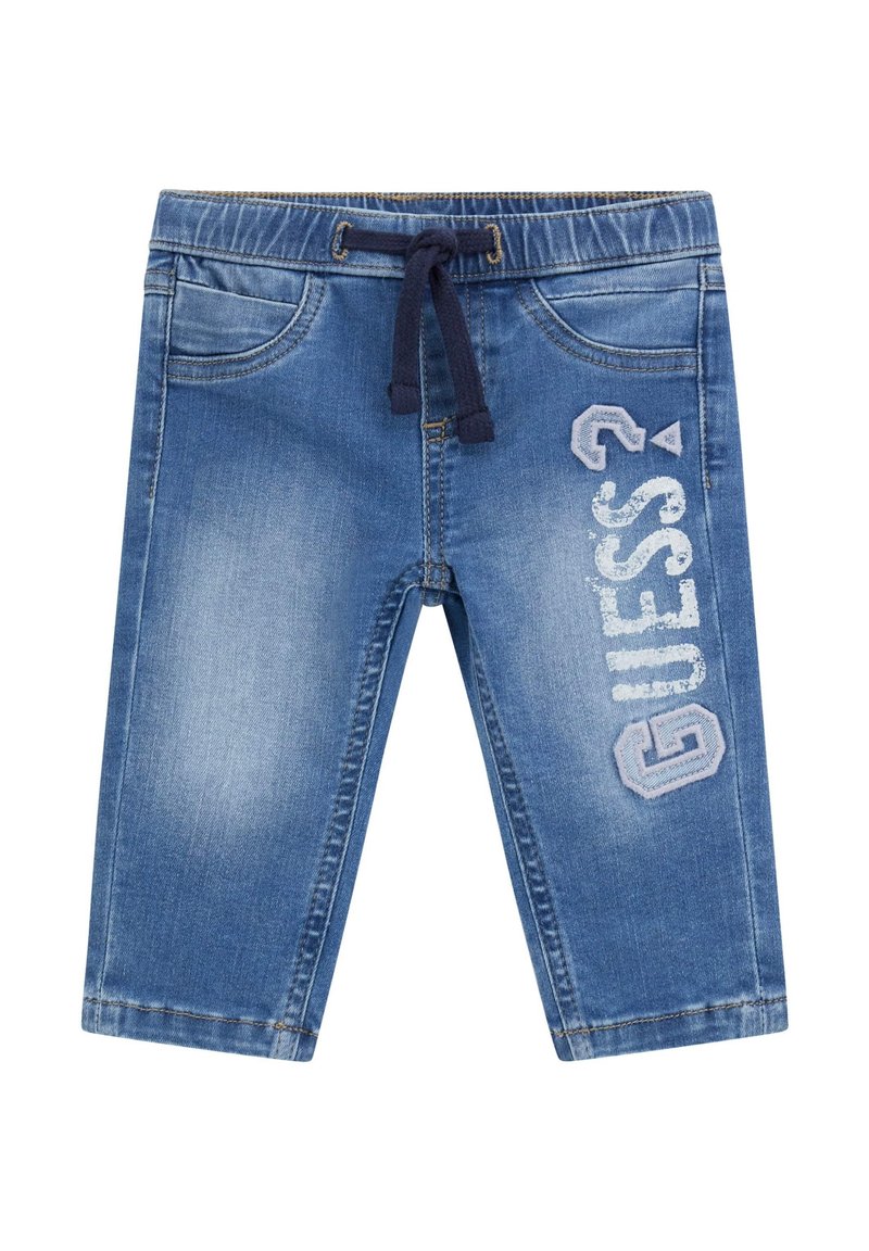 Vaatehousut vaaleansinisinä, joissa on elastinen vyötärö, naru, etutaskut ja sivussa valkoisella ja sinisellä "GUESS" brodattu logo.