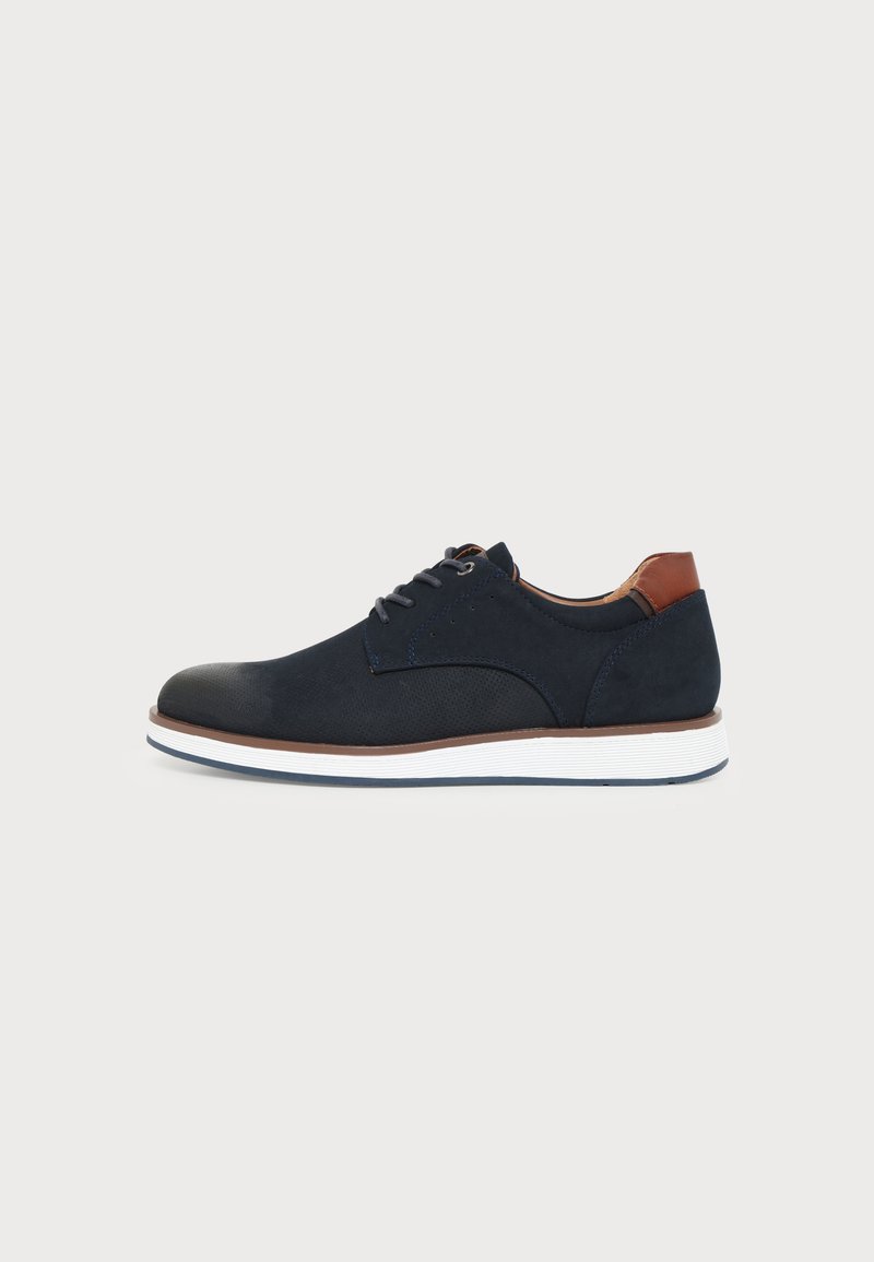 Chaussure décontractée bleu marine à lacets avec semelle blanche et accent marron au talon, profil bas, conçue pour un usage quotidien.