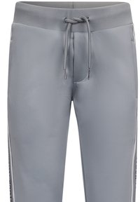 Grijze sportieve joggers gemaakt van een soepele, rekbare stof. Kenmerken zijn een elastische tailleband, trekkoordsluiting en zijstrepen met tekst.