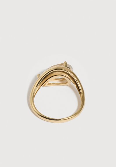 Χρυσό δαχτυλίδι με λείο, ακανόνιστου οβάλ σχήματος δακτύλιο και μεγάλο διαφανές πολύτιμο λίθο σε στήριγμα με νύχια.