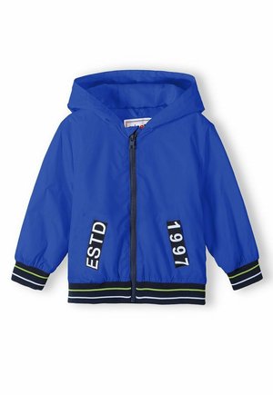 Veste d'enfant bleue à capuche avec fermeture éclair devant, poignets et ourlet rayés, et écussons noirs avec les inscriptions "ESTD" et "1997" à l'avant.