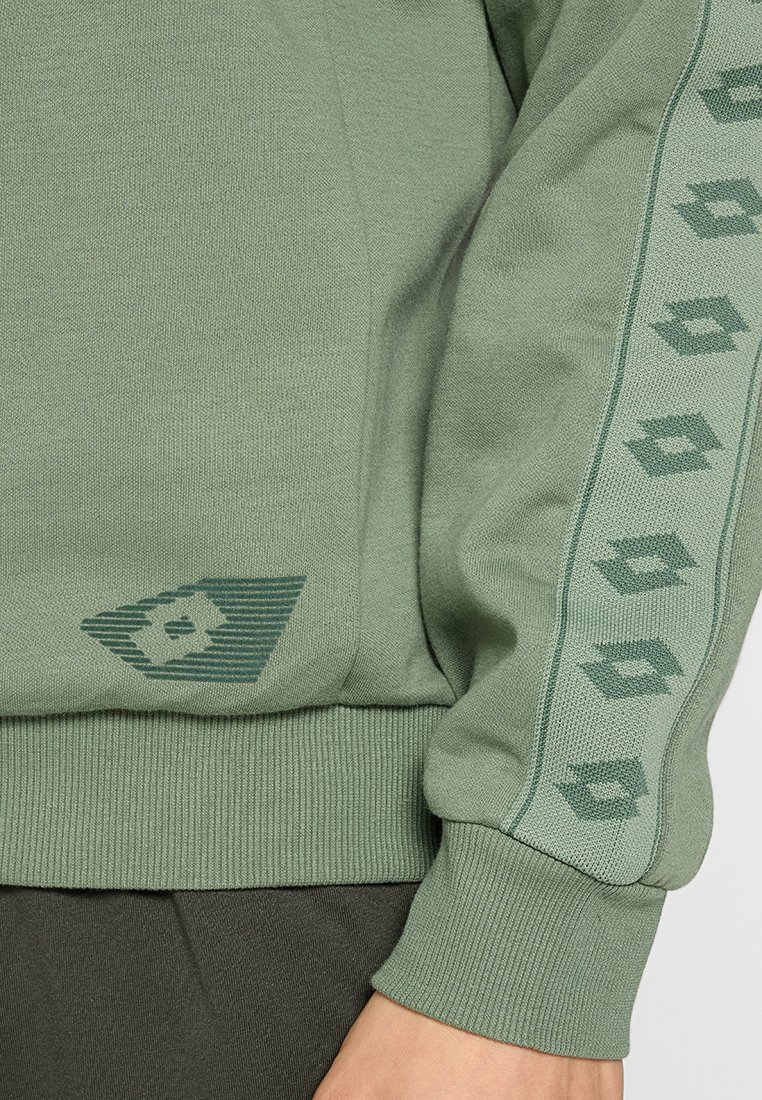 Zielona bluza z miękkiego materiału, z prążkowanym wykończeniem, wzorzystym akcentem na rękawie oraz geometrycznym logo w dolnym rogu.