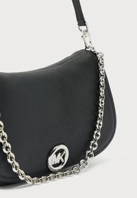 Μαύρη δερμάτινη τσάντα χειρός με υφή, αλυσίδα ασημί λουρί και κυκλικό ασημένιο λογότυπο μπροστά. Καμπυλωτό σχήμα με κομψό σχεδιασμό.