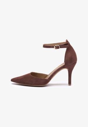 Chaussure à talons hauts en daim marron avec bout pointu, bride de cheville avec boucle dorée, et talon fin pour une silhouette élégante.