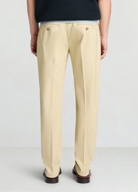 Beige maßgeschneiderte Hose mit glatter Stoffstruktur, ausgestattet mit Gesäßtaschen und goldfarbenen Knöpfen sowie einem geraden Bein.