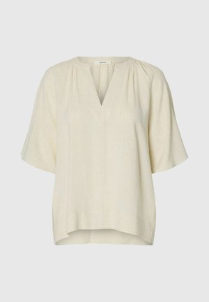 Blusa suelta de color crema con mangas cortas y escote en V con detalle de tela fruncida alrededor del cuello.