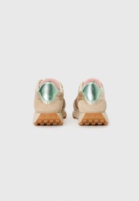 Baskets en nubuck beige avec intérieure en fausse fourrure rose, accents métalliques menthe sur le talon, et semelle en caoutchouc texturée avec un motif en nid d'abeille.