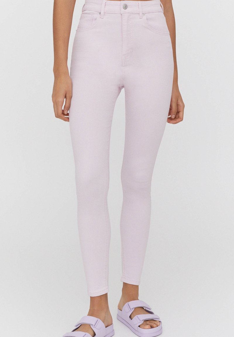 Jean skinny rose clair avec une coupe ajustée. Dispose d'une fermeture avant par bouton et fermeture éclair, de passants pour ceinture et de deux poches avant. Texture de tissu lisse.