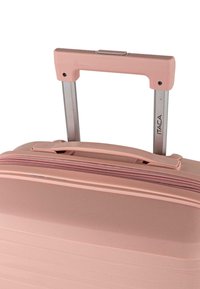 Maleta rígida rosa con superficie texturizada, asa metálica doble extensible y cremallera rosa. Logo de la marca visible en el lateral.