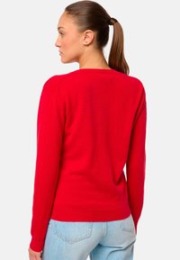 Pull en tricot rouge avec des manches longues, un col rond et un ourlet côtelé. Texture lisse, design ajusté et une construction simple à l'arrière.