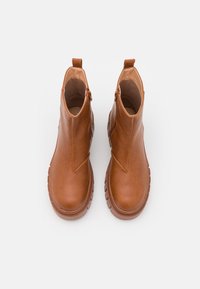 Stivali ankle marroni realizzati in pelle liscia. Presentano una suola spessa, un design sobrio e una chiusura con zip angolata sul lato interno.