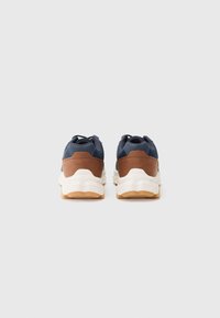 Men's athletic shoes with a navy blue upper, brown leather accents, white midsole, and gum rubber outsole. Rear view displayed.