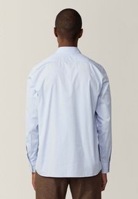 Camisa de manga larga a rayas azul claro con cuello clásico y puños abotonados, que presenta una textura suave y un corte recto.