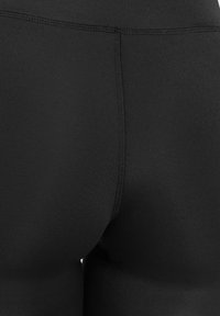 Close-up view of black fitted fabric with central seam, showing smooth texture and stitching details.
