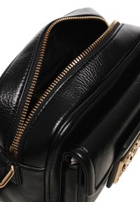 Borsa a mano in pelle nera con zip dorata parzialmente aperta, che mostra il materiale testurizzato e il design strutturato.