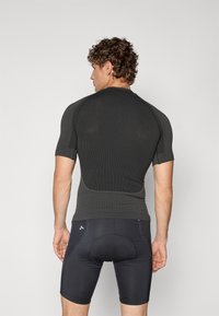 Kortærmet, mørkegrå atletisk skjorte med tekstureret mønster og tætsiddende design, parret med sorte kompressionsshorts med detaljer.
