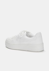 Białe sneakersy o gładkiej fakturze, zaokrąglonym kształcie i amortyzowanej podeszwie. Cechy to zapięcie na sznurówki oraz subtelne przeszycia po bokach.
