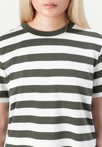 Randig t-shirt i olivgrön och vit. Rund halsringning, korta ärmar, tillverkad av mjuk bomullsblandning, med horisontella ränder i lika bredder.