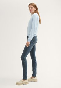 Gaiši zils, svītrains džemperis ar ribotām aprocēm, apvienots ar tumši zilām šaurām džinsām un krēmkrāsas platformas slīdējamām kurpēm. Vienkāršs, ikdienišķs apģērbs.