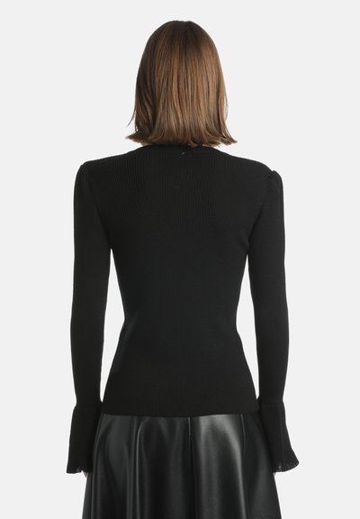 Pulover negru cu nervuri, cu mâneci lungi și manșete evazate. Spatele are un design ajustat, realizat dintr-un material tricotat moale, texturat.
