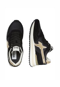 Sneaker neri e beige con suole bianche, logo a stella laterale, dettagli in mesh e suede, una scarpa vista frontale, una scarpa vista laterale.