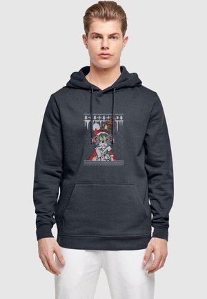 Mørkegrå hoodie med en frontlomme, prydet med et grafisk design af en tegneseriekat i en rød kappe. Materialet ser blødt og tekstureret ud.