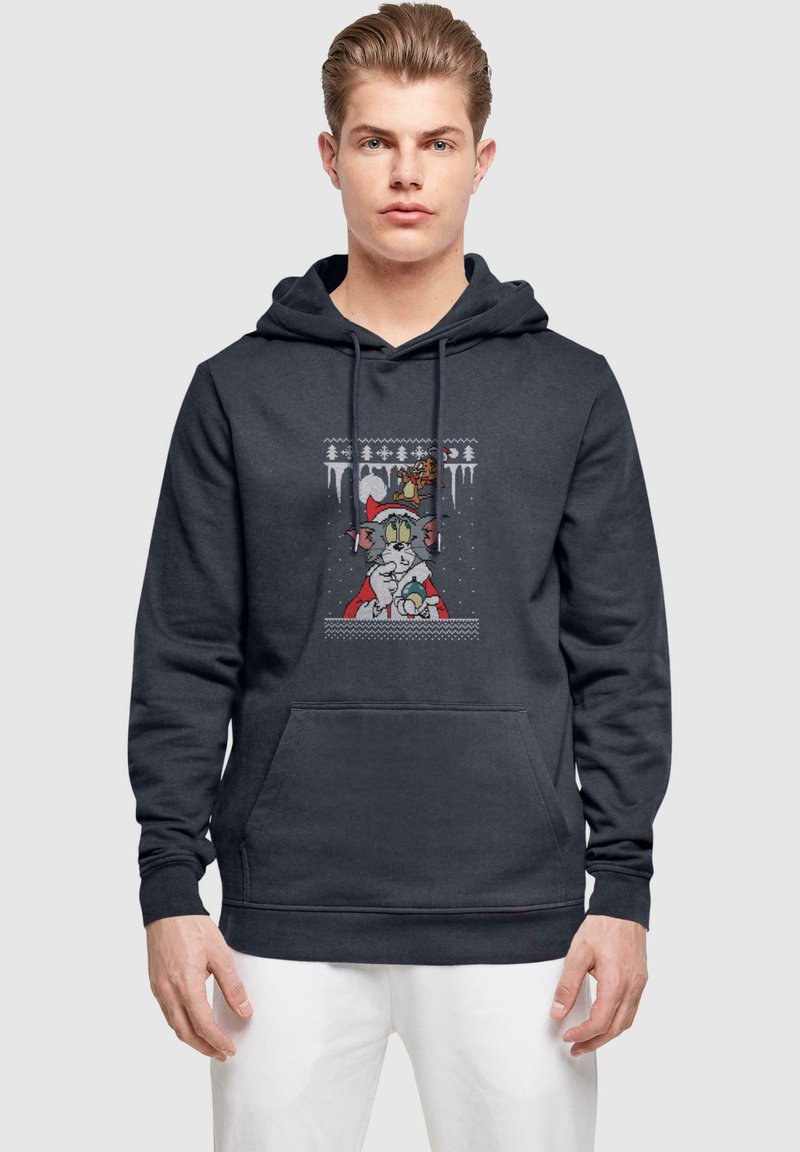 Mörkgrå hoodie med en framficka, med en grafisk design av en tecknad katt i en röd kappa. Materialet verkar mjukt och texturerat.