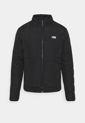 Veste noire matelassée avec col montant, fermeture éclair devant, deux poches latérales zippées et petit écusson rectangulaire avec logo sur la poitrine.