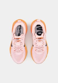 Zapatillas deportivas de color rosa claro con suelas naranjas. Parte superior de malla con detalles en negro y reflectantes. Cordones y texto "RUN" en la lengüeta.