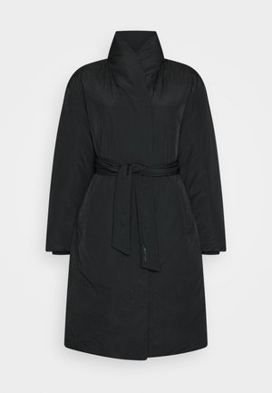 Manteau matelassé noir longueur genou avec un col montant, manches longues, poches latérales et ceinture nouée à la taille sur fond uni.