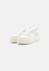 Sneakers bianchi in pelle con suola in gomma testurizzata, caratterizzati da pannellature bianche a contrasto e lacci piatti. Punta arrotondata e linguetta sul tallone.