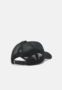 Svart netting trucker cap med en solid svart frontpanel, buet skygge, justerbar snapback-lukking, og en logo på den indre foringen.