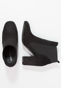 Stivaletti neri in suede con tacco a blocco, dotati di pannelli laterali elastici e un design a punta rotonda per una facile vestibilità.