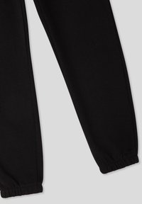 Pantaloni della tuta neri in tessuto morbido, con polsini elastici e vestibilità comoda. Design semplice senza motivi o accenti visibili.
