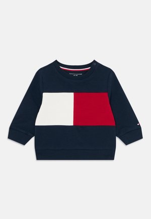 Sweatshirt para crianças numa tonalidade azul escuro, com punhos canelados, apresentando um bloco de cores retangulares em vermelho e branco no peito e um pequeno logotipo na manga.