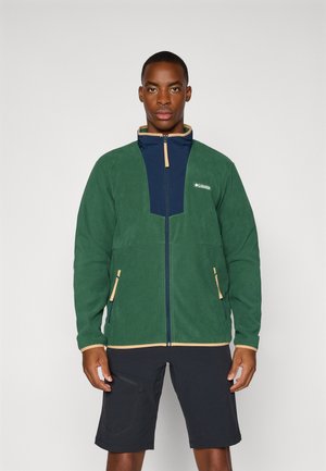 Green fleece jacket with navy front panel, beige zipper accents, two side pockets, and high collar design. Features Columbia logo on chest.