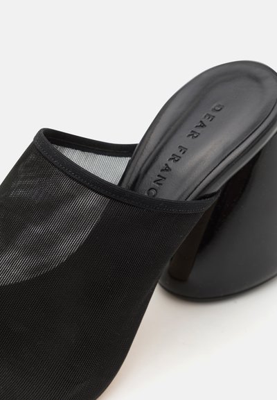 Schwarze Netz-Mulesandale mit einem gebogenen Absatz, glattem Innenbereich und einem eleganten Design mit einer subtilen strukturierten Oberfläche.