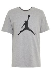 Šedé tričko s krátkým rukávem s černou siluetou basketbalisty, který skáče a drží míč jednou rukou.