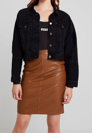 Veste en denim noir avec des boutons argentés, design cropped et poches avant, associée à une jupe crayon en simili cuir marron avec des coutures décoratives.