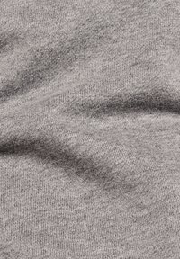 Tela de punto gris con una textura suave, mostrando sutiles variaciones en el tono y un delicado patrón acanalado a lo largo de toda la superficie.