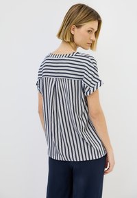 Top a maniche corte a righe in navy e bianco, con scollatura tonda e una vestibilità ampia e rilassata, caratterizzato da una piega sul retro.