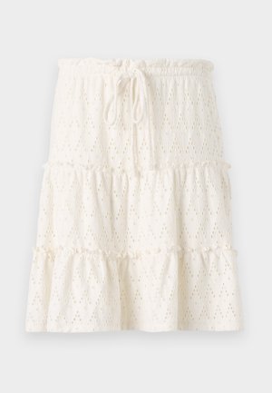 Falda blanca de capas con un patrón de ojales, cinturilla elástica con cordón y dobladillo con volantes, hecha de tejido ligero.