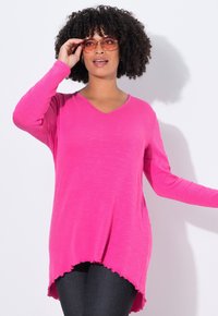 Camicia a maniche lunghe rosa con scollatura a V, caratterizzata da una vestibilità rilassata e orlo scallop. Il tessuto sembra leggero con una sottile trama.