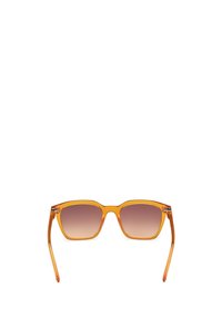 Gafas de sol cuadradas con montura transparente naranja, lentes marrones degradados y líneas limpias. Mínimo hardware en los laterales.
